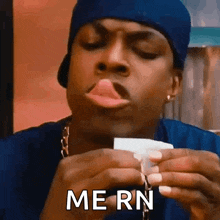 a man in a blue hat is holding a piece of paper with his tongue out and the word mern written on it .