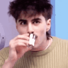 a young man is blowing his nose with a nasal spray .