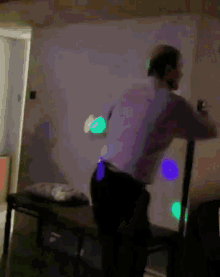 a man is standing in a dark room with purple lights on the wall