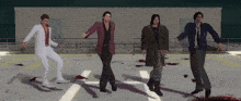 a group of men are dancing on a concrete floor