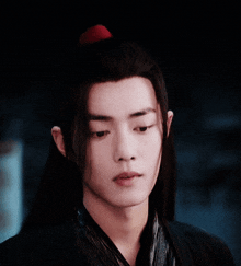 a young man with long black hair has his eyes closed