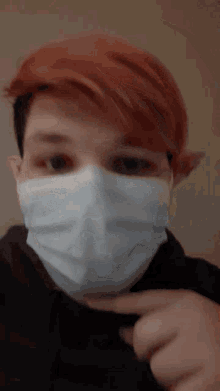 a person with red hair is wearing a face mask and pointing