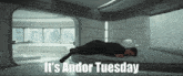 a man laying on a bed with the words " it 's andor tuesday " below him