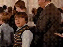 a man in a suit is standing next to a young boy in a striped vest .