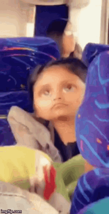 a little girl sitting on a bus with a funny face