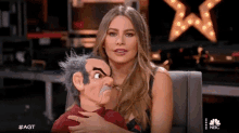 a woman is holding a puppet with a nbc logo in the corner