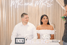 a man and a woman sit at a table with a sign that says mr and mrs