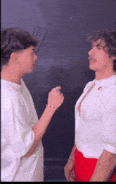 two men are standing next to each other and talking to each other .