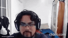 a man with a beard wearing headphones and glasses is looking at the camera .