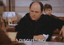 a man sitting at a table with the word disgusting written on the screen