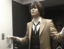 a man in a suit and tie is standing in front of a door that has the number 051 on it