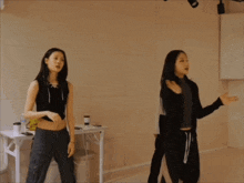 two girls are dancing in front of a mirror in a dance studio