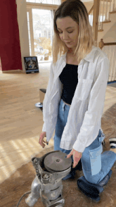 a woman in a white shirt is kneeling down in front of a machine that has a disc in it