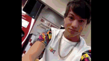 a young man is taking a selfie in front of a vending machine that says coca cola