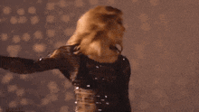 a woman in a black sequined dress is dancing with her arms in the air .