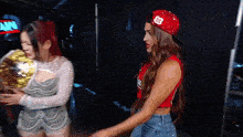 a woman wearing a red hat with the number 23 on it stands next to another woman