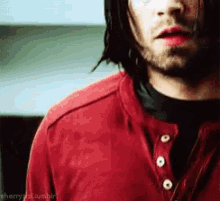 a close up of a man wearing a red shirt and black shirt