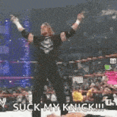 a wrestler is standing in a wrestling ring with his arms in the air and says suck my knick !!!