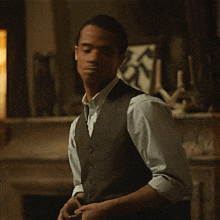 a man in a vest and white shirt is making a gesture