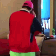 a man wearing a pink hat and a red shirt is talking on a cell phone
