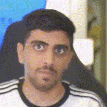 a close up of a man 's face with a beard wearing a white shirt .