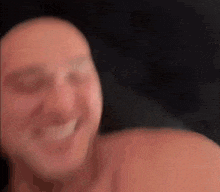 a man without a shirt is smiling and looking at the camera in a blurry photo .
