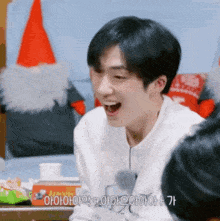 a young man is laughing with his mouth wide open in front of a santa hat