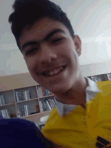 a young man in a yellow adidas shirt smiles for the camera