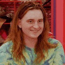 a woman with long red hair is wearing a green tie dye shirt
