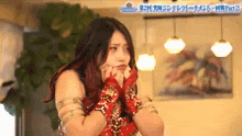 a woman in a red dress and red gloves is making a face .