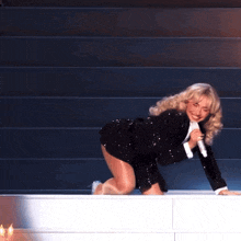 a woman in a black dress is kneeling down with a microphone