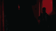 a woman with long white hair wearing sunglasses and a choker is walking in a dark room .
