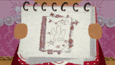 a person is holding a piece of paper with a drawing of a book and the letters cc on it