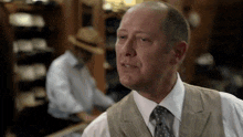 a man wearing a vest and tie looks at the camera