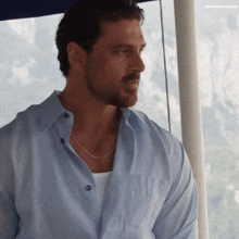 a man wearing a light blue shirt and a chain around his neck
