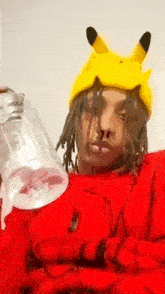 a man wearing a pikachu hat is holding a plastic bottle of water