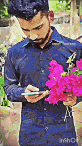 a man holding a bouquet of pink flowers and looking at his phone