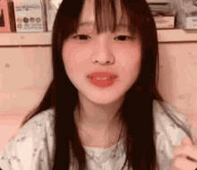 a young girl with long hair is making a funny face while sitting on a bed .