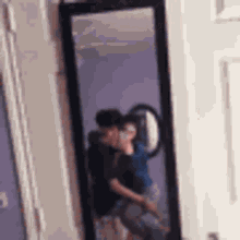 a man is taking a picture of himself and another man in a mirror .