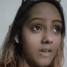 a close up of a woman 's face with a nose ring and glasses .