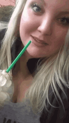 a woman drinking a milkshake with a green straw in her mouth