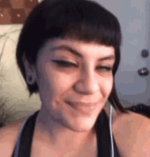 a woman with short black hair is smiling and making a face .