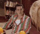 a man wearing a red and green striped shirt looks at a woman