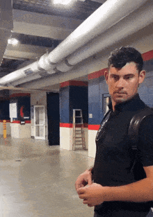 a man in a black shirt is standing in a hallway with a yellow sign that says ' emergency exit ' on it