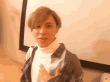 a woman wearing a white turtleneck and plaid shirt is standing in front of a projector screen