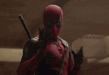 a man in a deadpool costume is holding a sword in his hands .