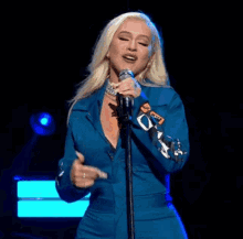 a woman singing into a microphone wearing a blue jacket