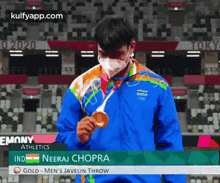 a man wearing a mask is holding a gold medal in front of a stadium .