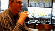 a man sits at a table in front of a window that says denver on it