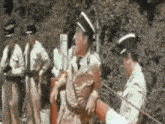 a group of men in military uniforms are standing next to each other smoking cigarettes .